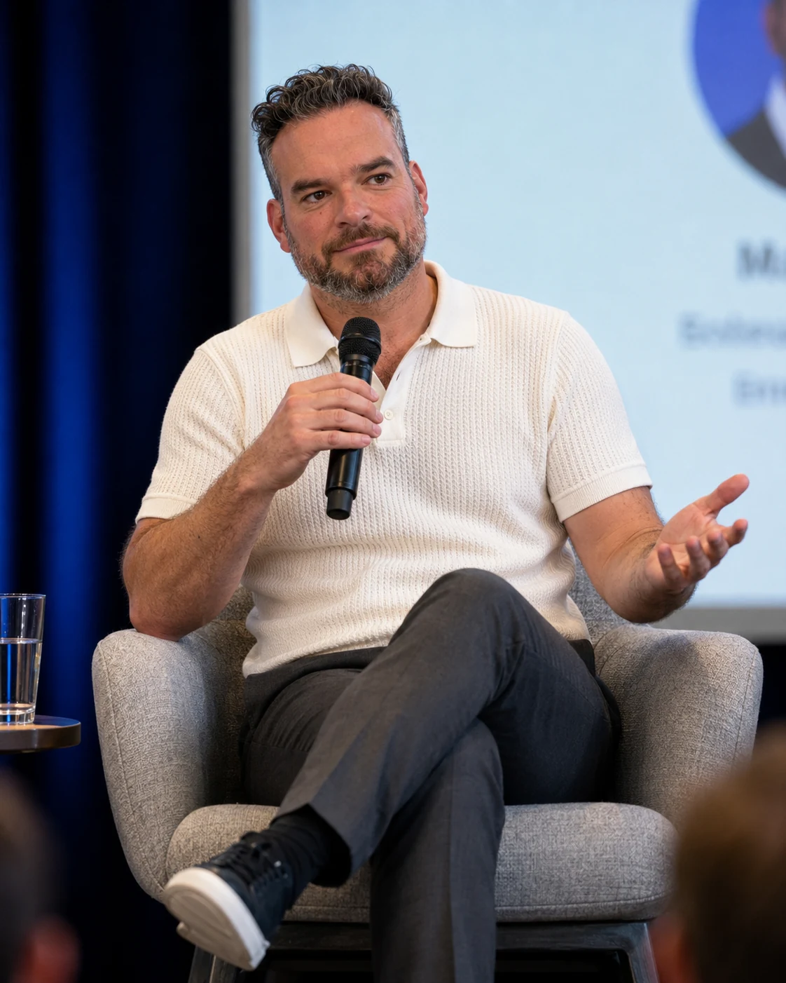 Micheal Sheehy seated on stage in conversation with a handheld microphone