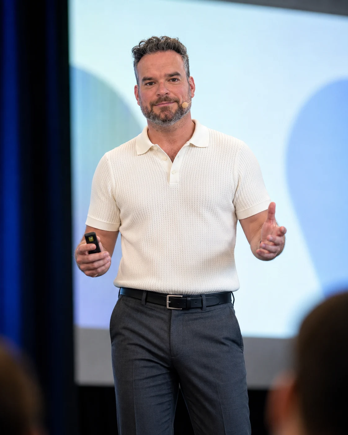 Micheal Sheehy speaking on stage in a cream polo shirt